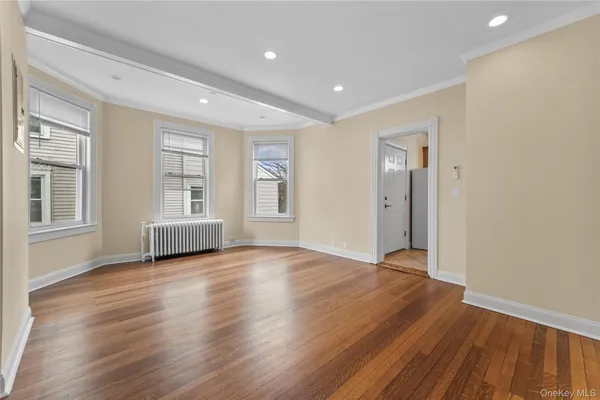 a view of an empty room with wooden floor and windows