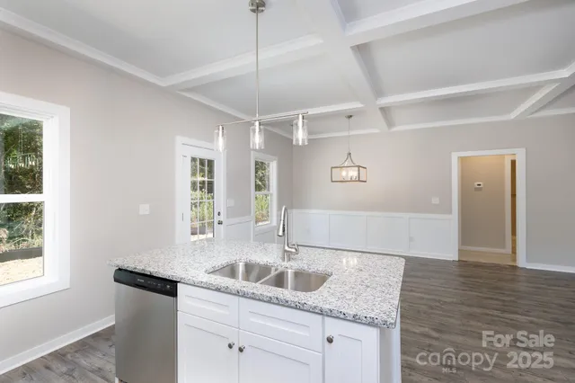 a kitchen with granite countertop a sink window and cabinets