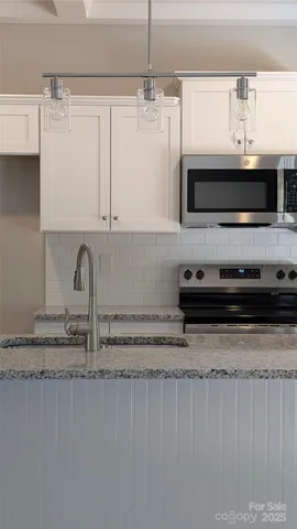 a kitchen with stainless steel appliances granite countertop a sink a stove and a microwave