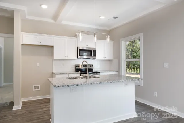 a kitchen with kitchen island granite countertop a sink window and cabinets