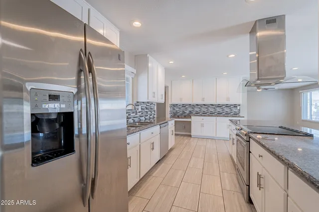 a large kitchen with stainless steel appliances kitchen island granite countertop a sink and cabinets