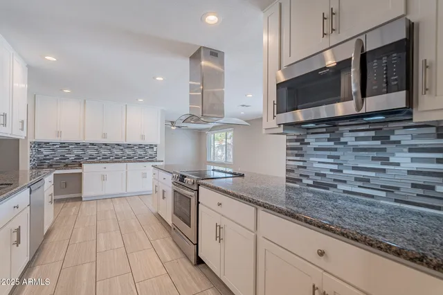 a kitchen with stainless steel appliances granite countertop a sink and a stove