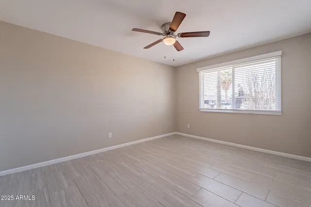 an empty room with wooden floor ceiling fan and window