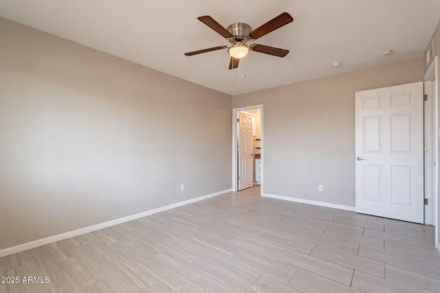 an empty room with wooden floor and a ceiling fan
