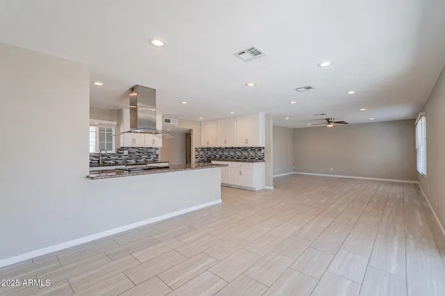 a view of kitchen and empty room with wooden floor
