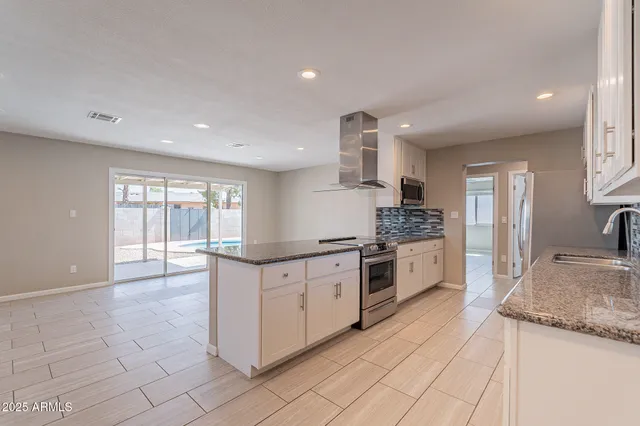 a large kitchen with granite countertop a stove and a sink