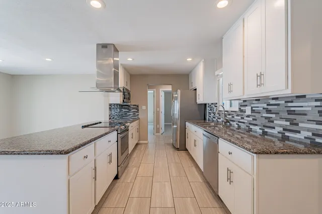 a kitchen with stainless steel appliances granite countertop a stove a sink and a refrigerator