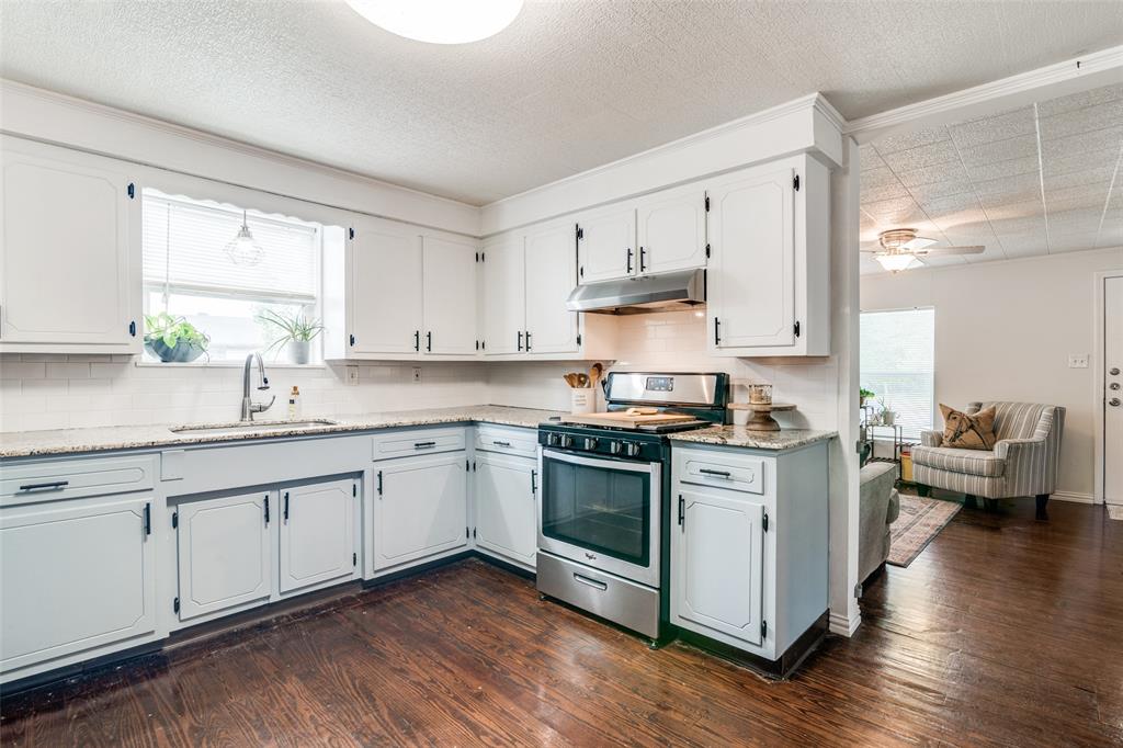 113 Caddo Street Josephine, TX 75173 - Photo 6 of 31 a kitchen with stainless steel appliances granite countertop a stove top oven a sink dishwasher and white cabinets with wooden floor