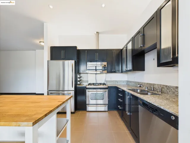 a kitchen with stainless steel appliances granite countertop a sink stove and refrigerator