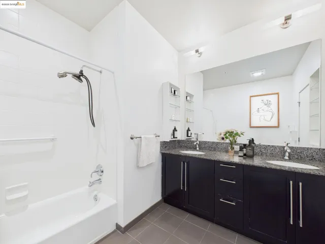a bathroom with a tub sink double vanity granite tub shower and mirror