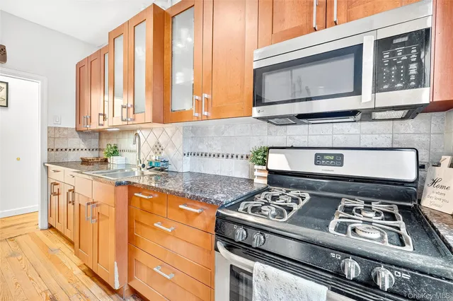 a kitchen with granite countertop wooden cabinets stove top oven and sink