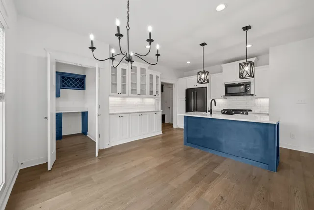 a large kitchen with stainless steel appliances granite countertop a stove a oven a a sink and a chandelier