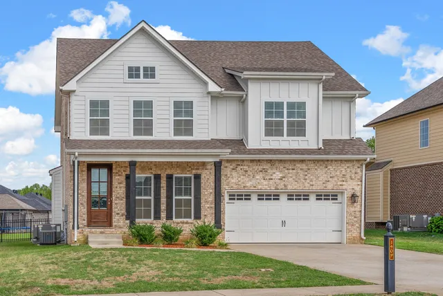 a view of a white house with large windows and a yard with plants and large trees