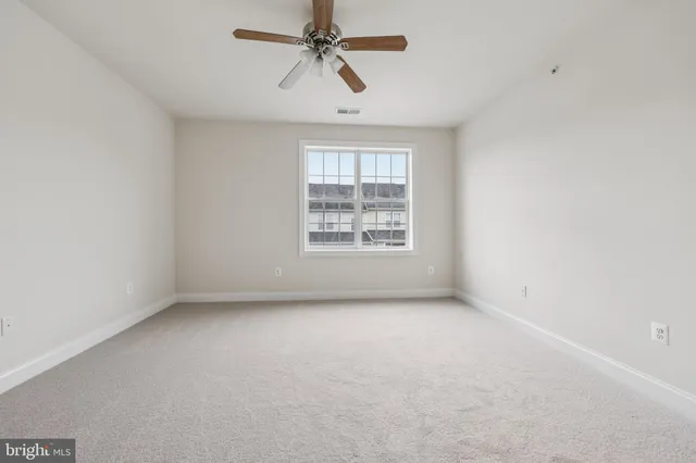 an empty room with a window and ceiling fan
