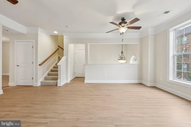 a view of empty room with wooden floor and fan