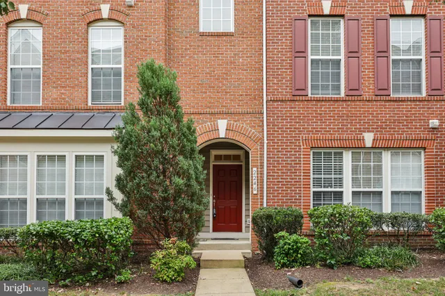 front view of a brick house with a large windows and potted plants