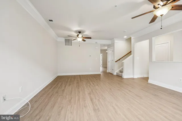 an empty room with wooden floor fan and windows