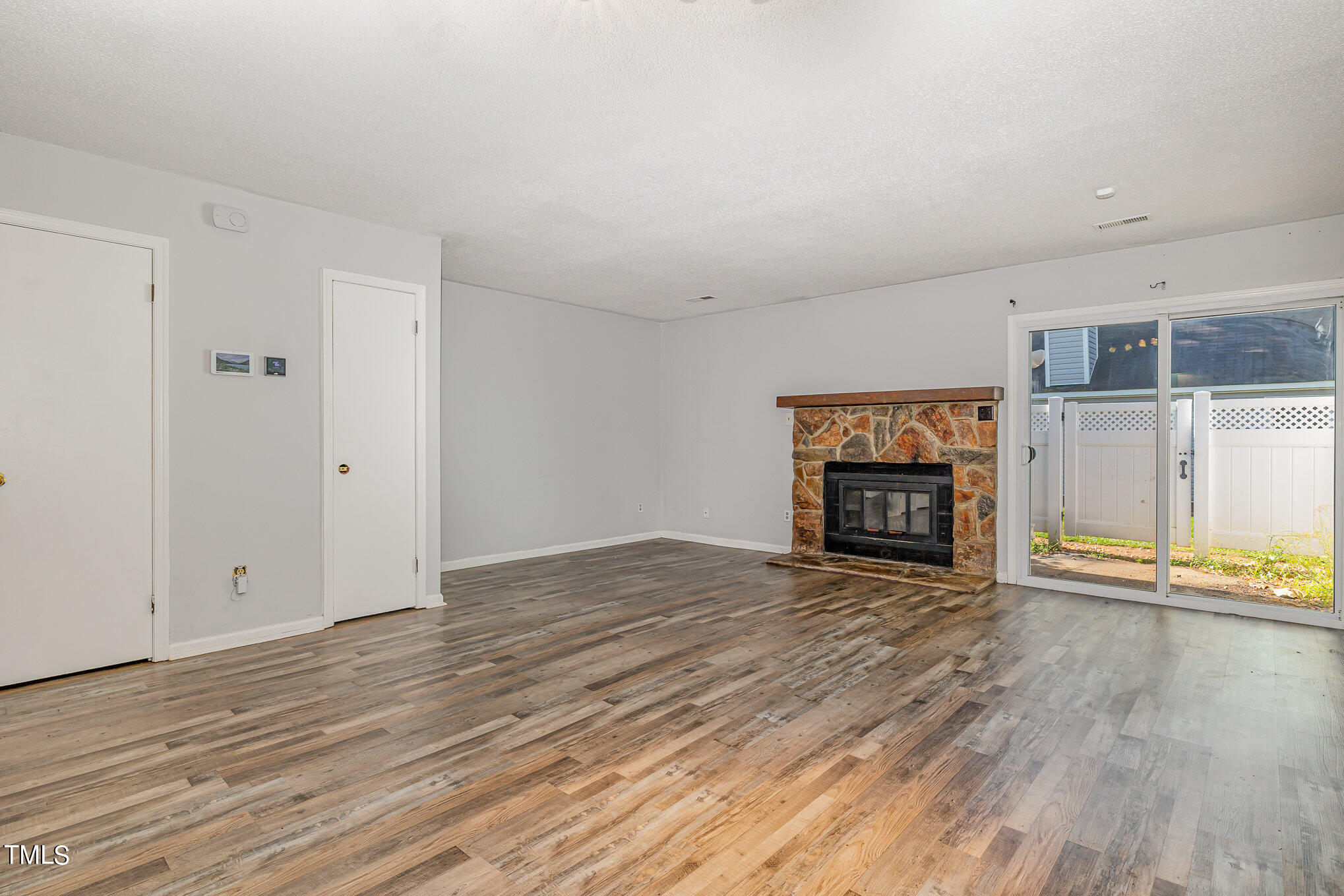 3702 San Pablo Drive Raleigh, NC 27616 - Photo 7 of 26 an empty room with wooden floor fireplace and windows