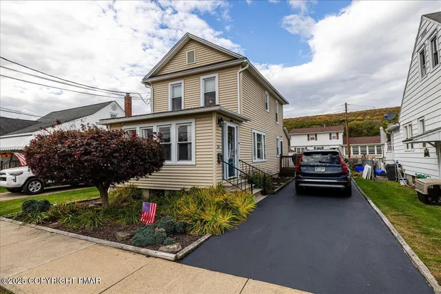 a view of a white house with large windows and a small yard