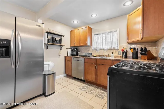 a kitchen with stainless steel appliances granite countertop a refrigerator a sink a stove and white cabinets