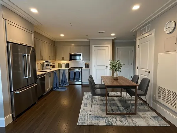 a kitchen with stainless steel appliances kitchen island granite countertop a refrigerator a stove a sink a dining table and chairs