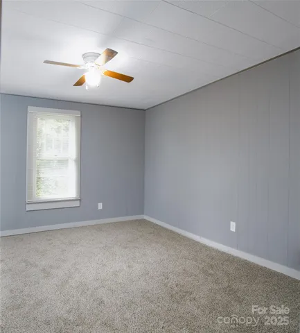 an empty room with window and chandelier fan