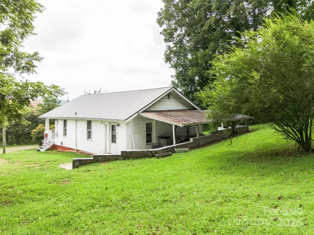 a view of a house with a yard potted plants and large tree