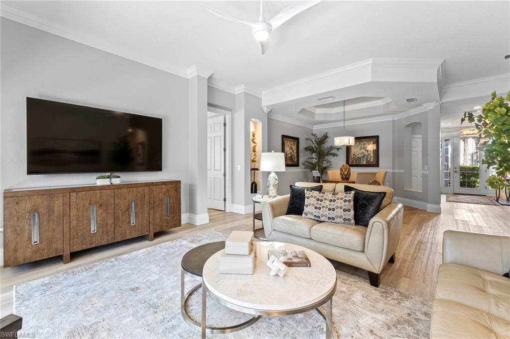 9041 Whimbrel Watch Lane, Unit 101 Naples, FL 34109 - Photo 12 of 34 Living area with wood finished floors, crown molding, a tray ceiling, and arched walkways