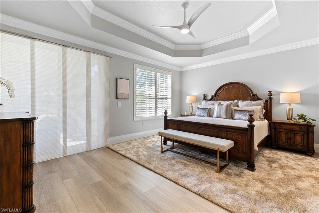 9041 Whimbrel Watch Lane, Unit 101 Naples, FL 34109 - Photo 14 of 34 Bedroom featuring ornamental molding, ceiling fan, light wood-type flooring, and a tray ceiling