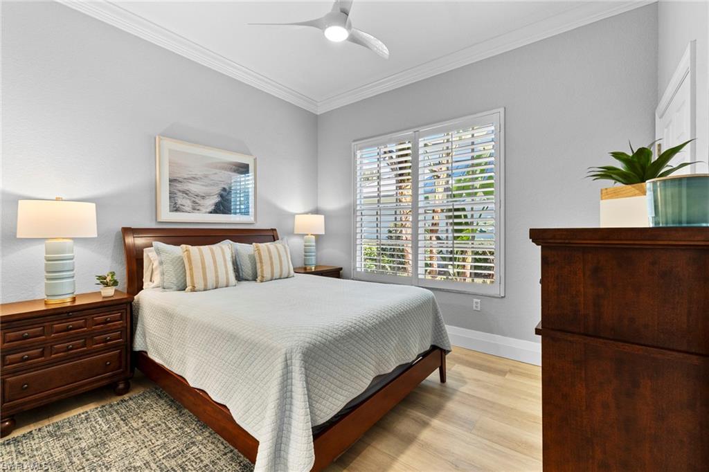 9041 Whimbrel Watch Lane, Unit 101 Naples, FL 34109 - Photo 27 of 34 Bedroom with crown molding, light wood-type flooring, and a ceiling fan