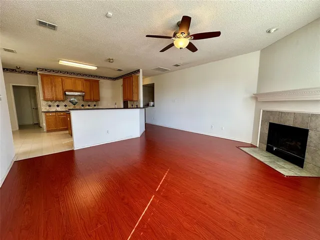 a view of a livingroom with a fireplace a ceiling fan and wooden floor