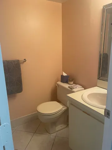 a white toilet sitting next to a white sink and a vanity