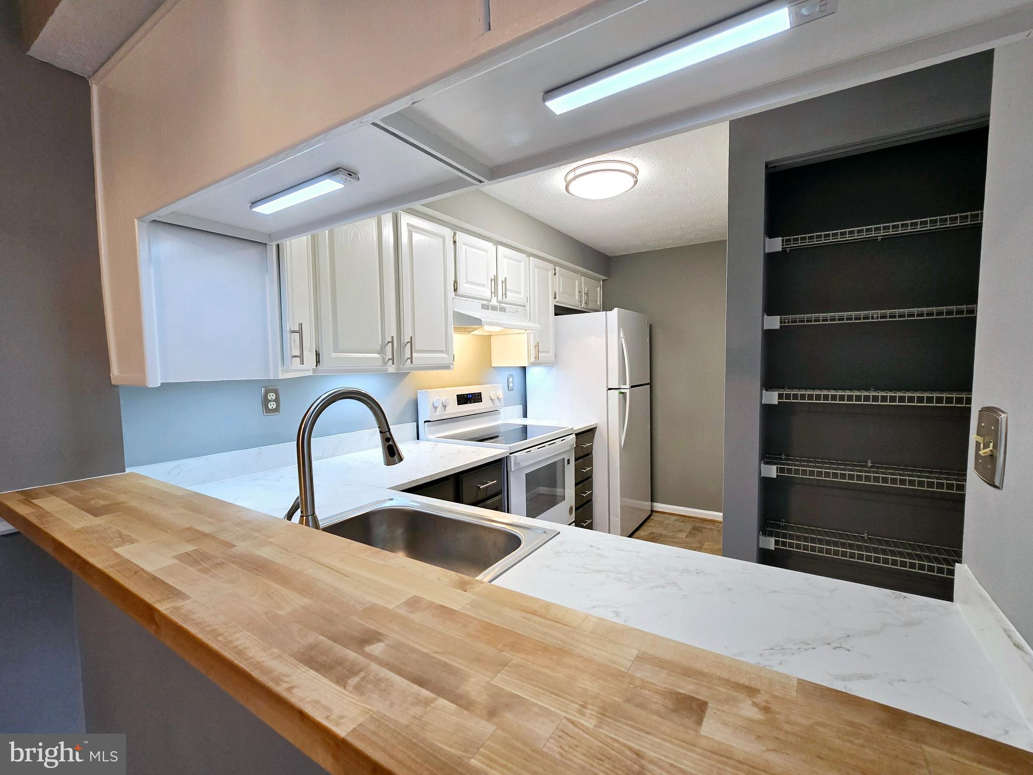 821 Stratford Way, Unit H Frederick, MD 21701 - Photo 12 of 45 a kitchen with stainless steel appliances kitchen island a stove a sink and a refrigerator