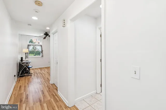 a view of a hallway with wooden floor and a bathroom