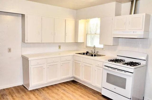 a kitchen with granite countertop white cabinets and white appliances