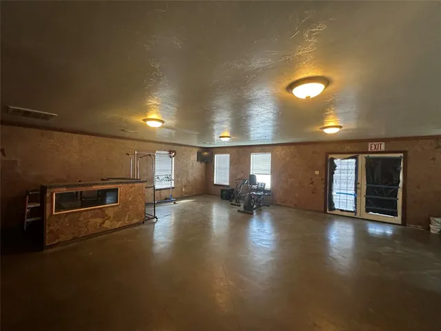 an empty room with wooden floor and a kitchen