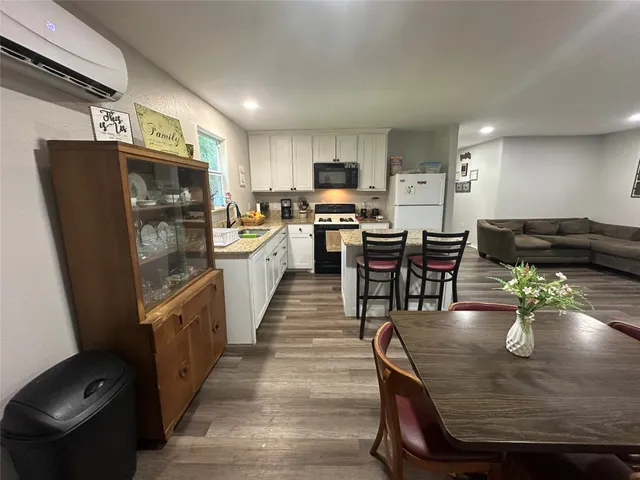 a kitchen with stainless steel appliances granite countertop a table chairs and a refrigerator