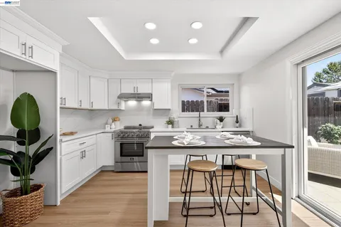 a kitchen with stainless steel appliances granite countertop a table chairs sink and cabinets