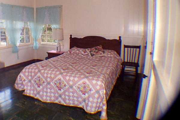 340 Mehana Road Eleele, HI 96705 - Photo 8 of 10 a bedroom with a bed and wooden floor