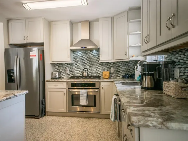 a kitchen with stainless steel appliances granite countertop a stove a refrigerator and a white cabinets