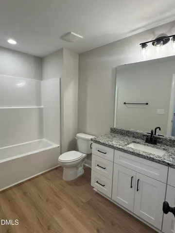 a bathroom with a granite countertop sink a toilet and bathtub