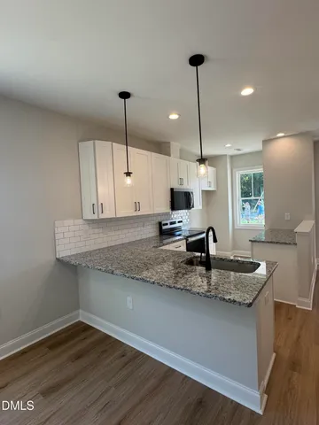 a kitchen with kitchen island granite countertop a sink a counter space appliances and cabinets