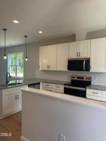 a kitchen with stainless steel appliances granite countertop a sink a stove a microwave a counter top and cabinets