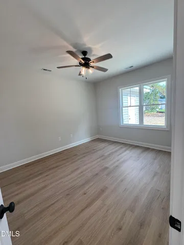 an empty room with wooden floor fan and windows