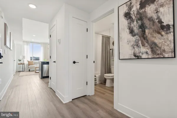 a view of a hallway with wooden floor and a bathroom
