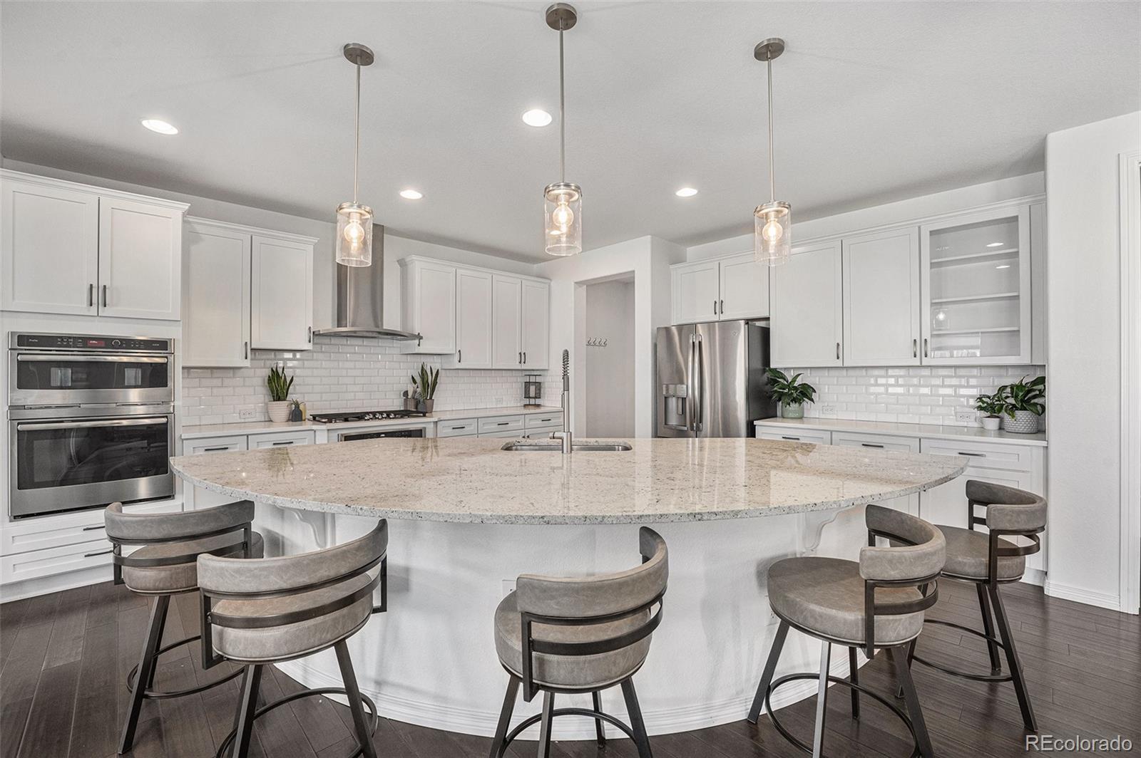 10610 Greycliffe Drive Highlands Ranch, CO 80126 - Photo 13 of 49 a kitchen with stainless steel appliances kitchen island granite countertop a dining table chairs refrigerator and microwave