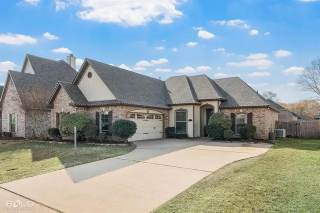 a view of a white house next to a yard with big trees