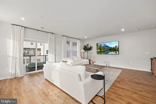 a living room with stainless steel appliances kitchen island granite countertop a sink and wooden floor