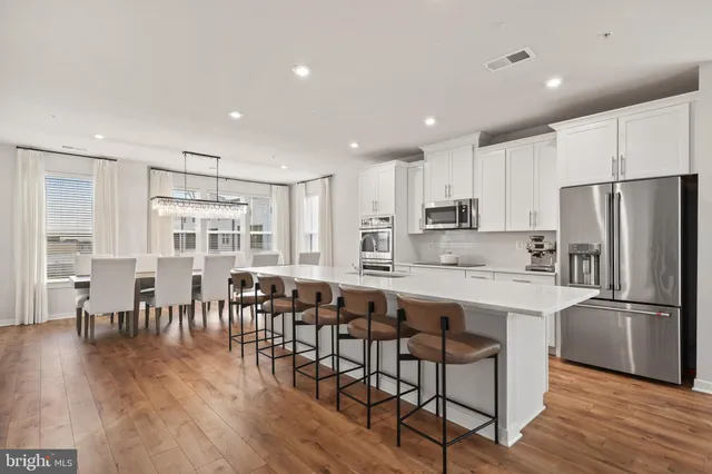 a kitchen with stainless steel appliances granite countertop a dining table chairs refrigerator sink and cabinets