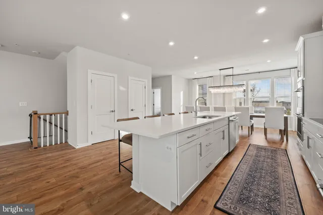 a large white kitchen with lots of counter space wooden floor and stainless steel appliances